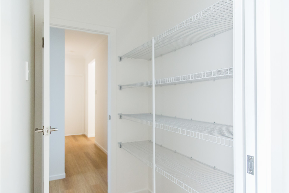 This is an example of a mid-sized contemporary gender-neutral walk-in wardrobe in Townsville with open cabinets, white cabinets, vinyl floors and brown floor.