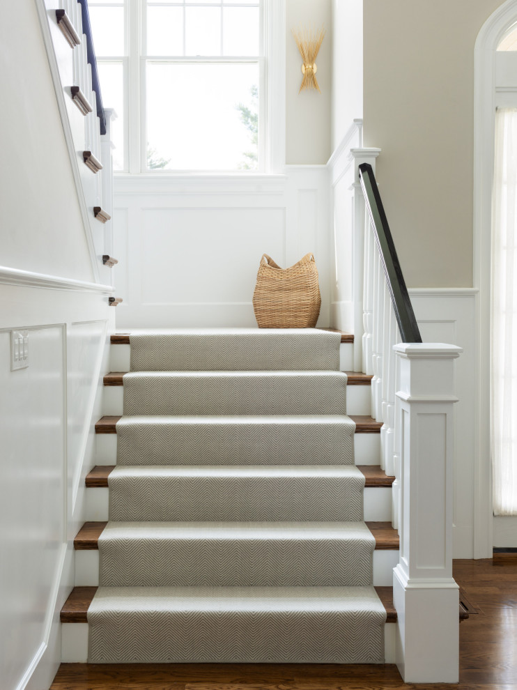 This is an example of a transitional carpeted u-shaped staircase in Boston with carpet risers and wood railing.