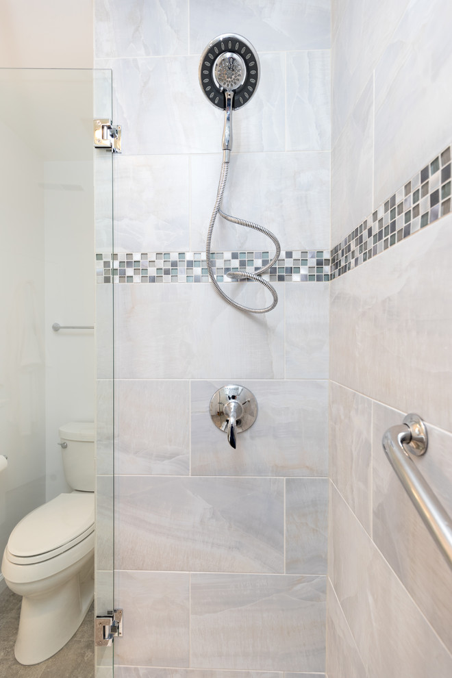 This is an example of a mid-sized transitional 3/4 bathroom in DC Metro with shaker cabinets, white cabinets, an alcove shower, a two-piece toilet, gray tile, white tile, porcelain tile, white walls, travertine floors, an undermount sink and quartzite benchtops.