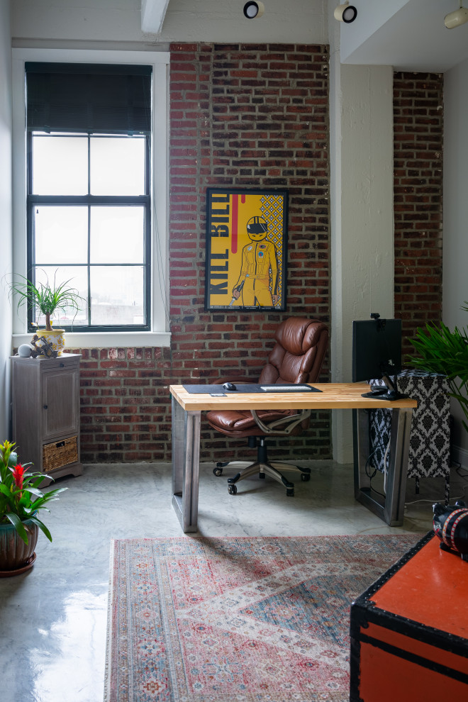 Imagen de despacho minimalista de tamaño medio con paredes rojas, suelo de cemento, escritorio independiente y suelo gris