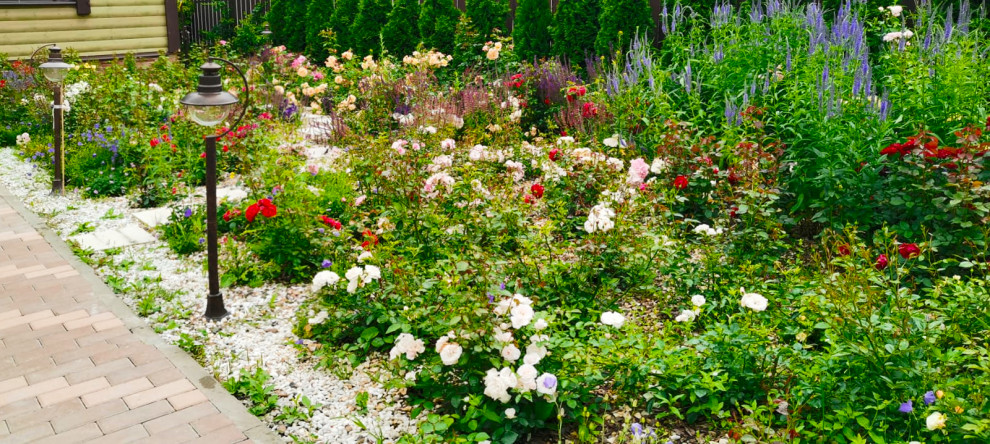 Aménagement d'un xéropaysage avant victorien de taille moyenne et l'été avec un massif de fleurs, une exposition ensoleillée, des pavés en béton et une clôture en bois.