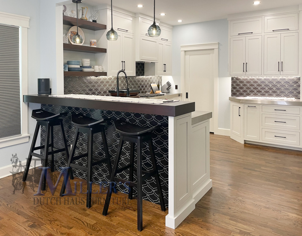 Inspiration for a large traditional u-shaped kitchen/diner in Tampa with white cabinets, stainless steel worktops, black splashback, black appliances, an island, brown floors and multicoloured worktops.