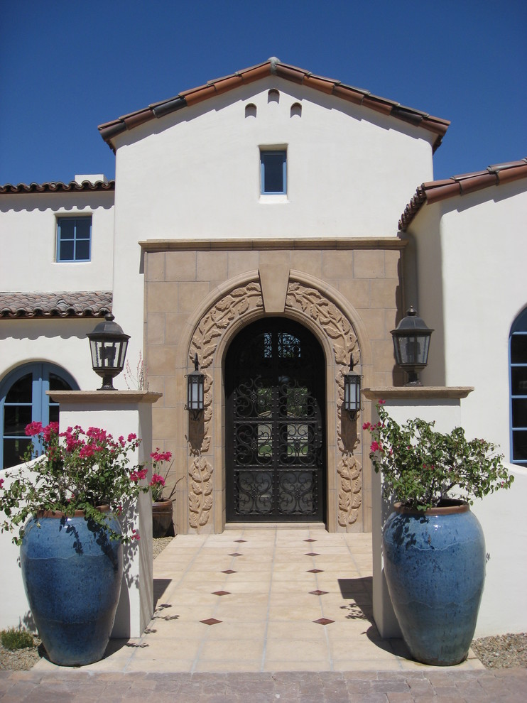 This is an example of a mediterranean front door in Phoenix with a metal front door.
