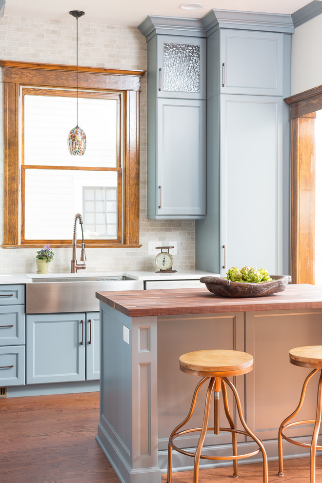 Mid-sized transitional kitchen in Atlanta with a farmhouse sink, recessed-panel cabinets, blue cabinets, wood benchtops, stone tile splashback, medium hardwood floors, with island and multi-coloured splashback.