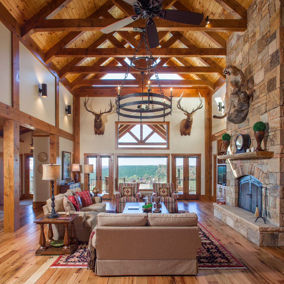 This is an example of an expansive country open concept living room in Other with medium hardwood floors, a standard fireplace, a stone fireplace surround, a built-in media wall and white walls.