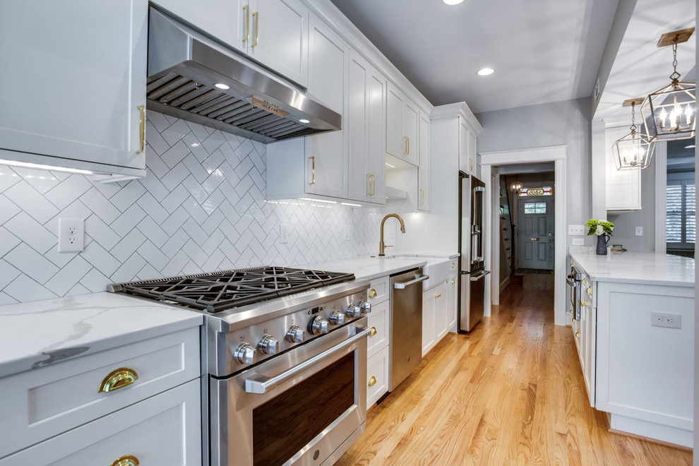 Mid-sized transitional galley light wood floor and beige floor eat-in kitchen photo in DC Metro with a farmhouse sink, shaker cabinets, white cabinets, quartz countertops, white backsplash, subway tile backsplash, stainless steel appliances, a peninsula and white countertops