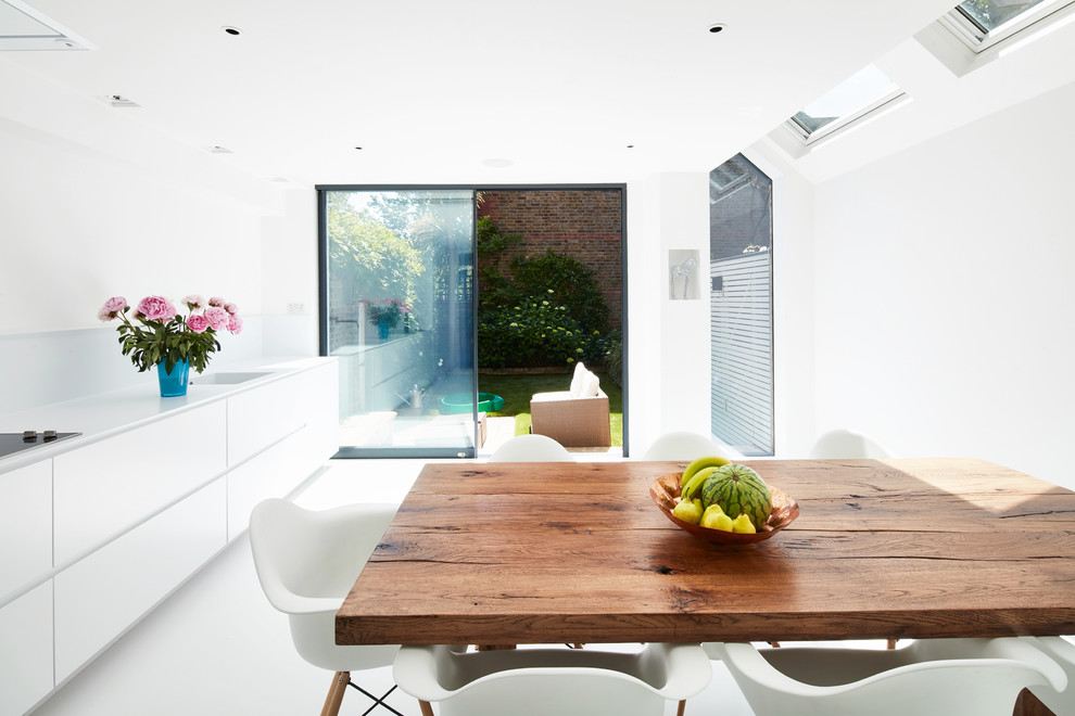 Large contemporary kitchen/dining room in London with white floors.