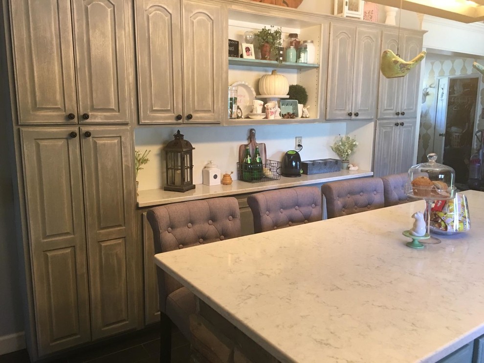 Design ideas for a mid-sized traditional l-shaped kitchen in Chicago with raised-panel cabinets, white cabinets, soapstone benchtops, white splashback, subway tile splashback, panelled appliances, dark hardwood floors, with island and brown floor.