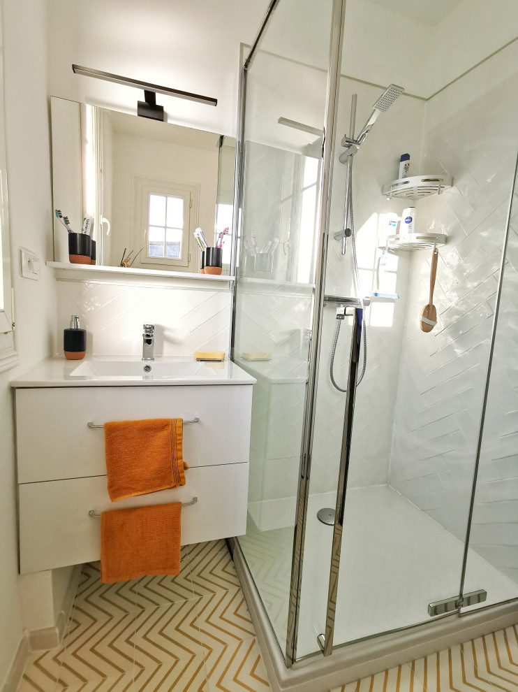 Foto på ett litet funkis vit badrum med dusch, med släta luckor, vita skåp, en dubbeldusch, en vägghängd toalettstol, vit kakel, keramikplattor, vita väggar, cementgolv, ett undermonterad handfat, gult golv och dusch med gångjärnsdörr