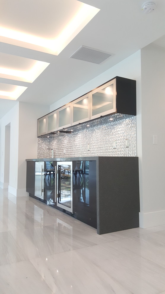 This is an example of a large contemporary single-wall home bar in Miami with no sink, flat-panel cabinets, black cabinets, concrete benchtops, grey splashback, metal splashback, marble floors and grey floor.