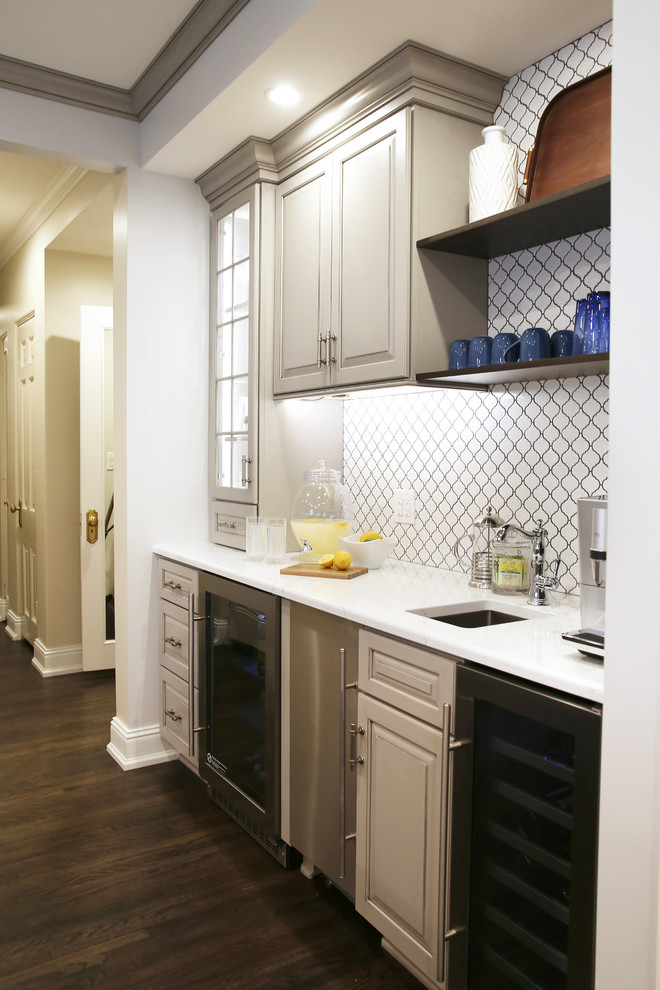 Large transitional l-shaped dark wood floor and brown floor enclosed kitchen photo with raised-panel cabinets, white backsplash, ceramic backsplash, stainless steel appliances and an island