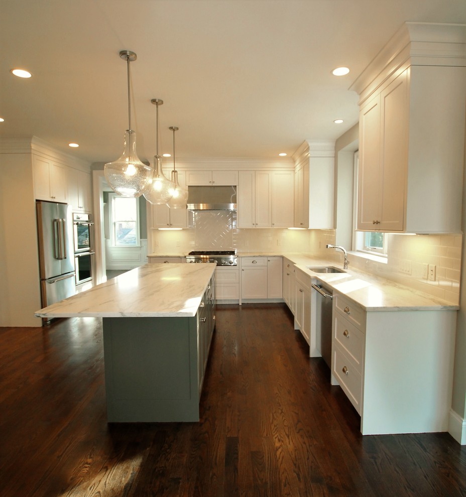 Example of a mid-sized transitional u-shaped dark wood floor and brown floor eat-in kitchen design in Boston with an undermount sink, shaker cabinets, white cabinets, marble countertops, white backsplash, porcelain backsplash, stainless steel appliances and an island