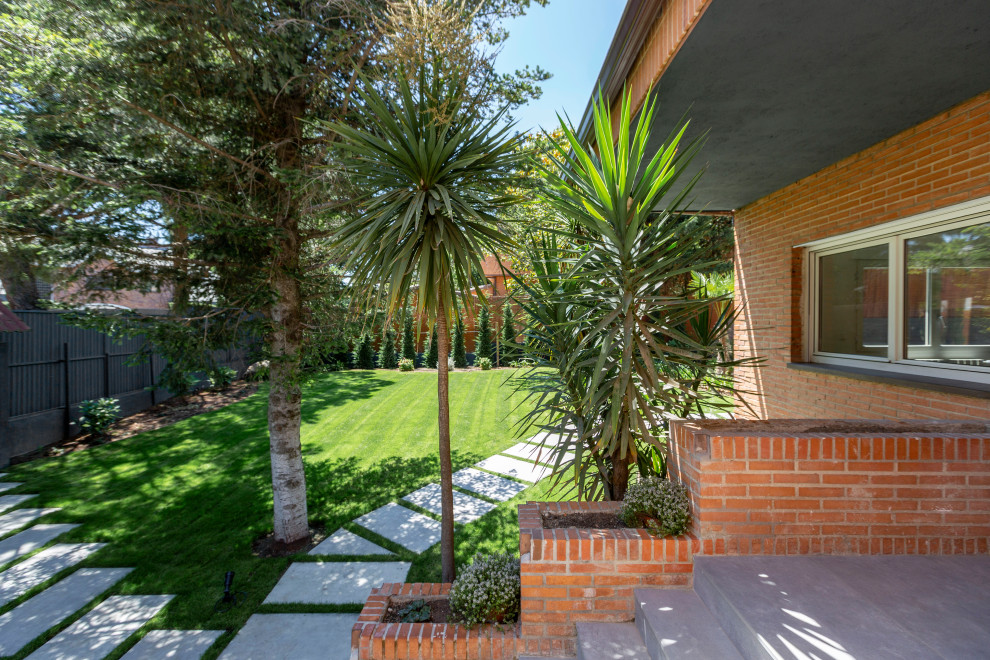 Large contemporary front yard partial sun garden in Madrid with with path and river rock.