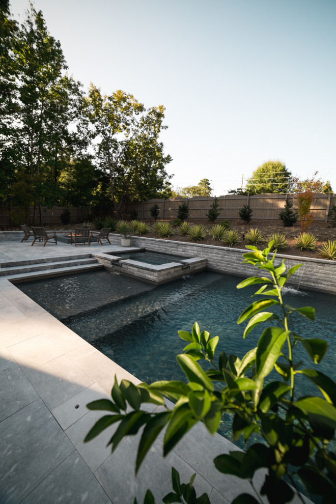 Ispirazione per una piscina monocorsia design rettangolare di medie dimensioni e dietro casa con una vasca idromassaggio e pavimentazioni in pietra naturale