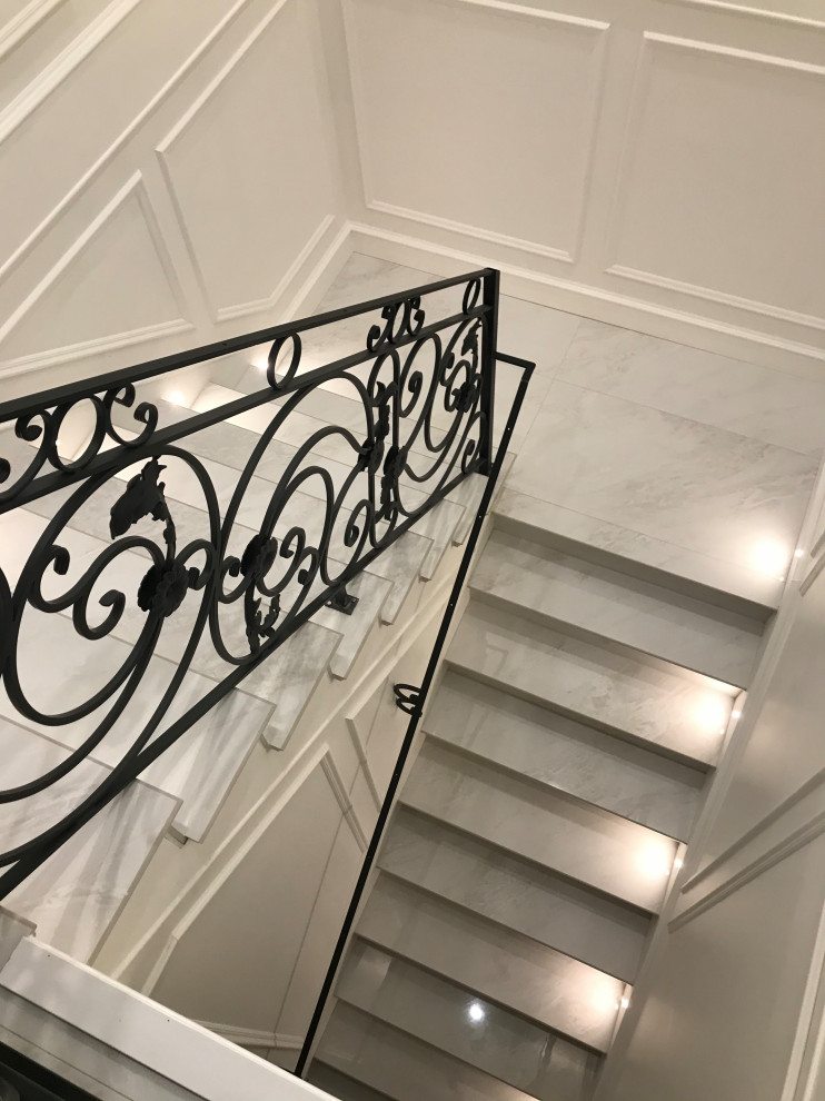 Inspiration pour un très grand escalier courbe victorien en marbre avec un garde-corps en métal, des contremarches en marbre et boiseries.