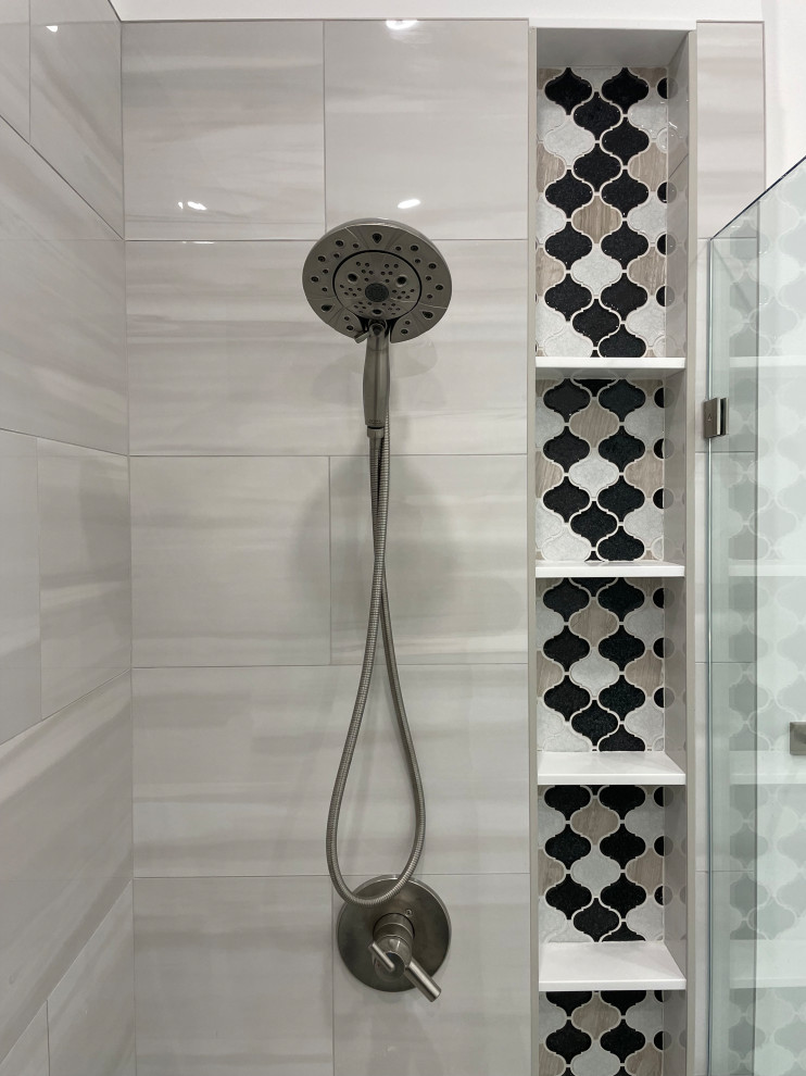 This is an example of a mid-sized modern master bathroom in DC Metro with recessed-panel cabinets, white cabinets, a corner shower, a two-piece toilet, gray tile, porcelain tile, white walls, porcelain floors, an undermount sink, marble benchtops, white floor, a hinged shower door, white benchtops, a niche, a double vanity and a freestanding vanity.