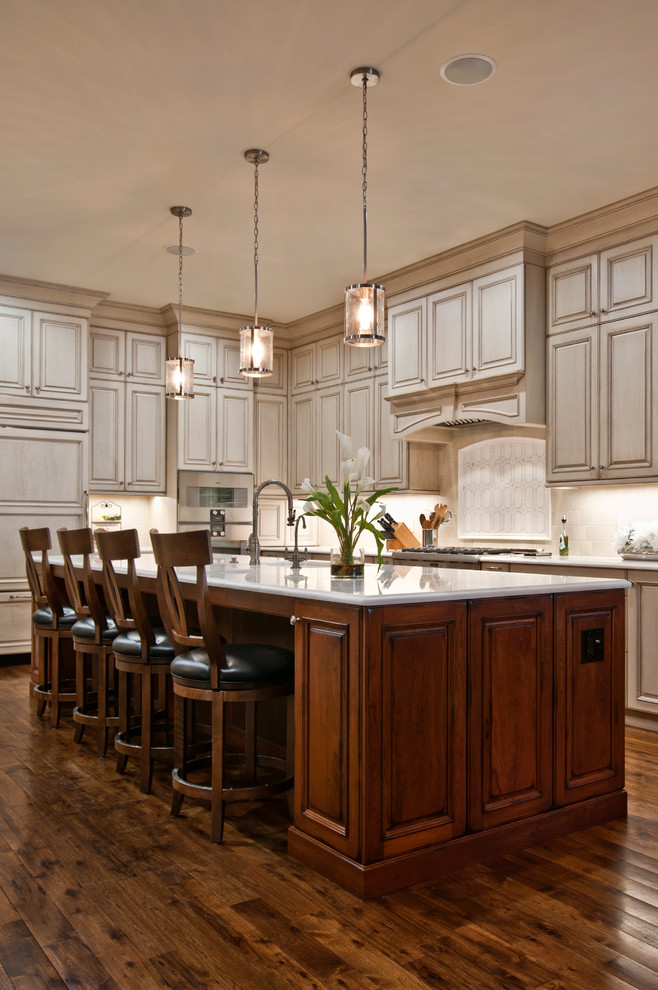 Inspiration for a large traditional l-shaped separate kitchen in Nashville with an undermount sink, raised-panel cabinets, beige cabinets, marble benchtops, beige splashback, ceramic splashback, panelled appliances, medium hardwood floors, with island, brown floor and white benchtop.