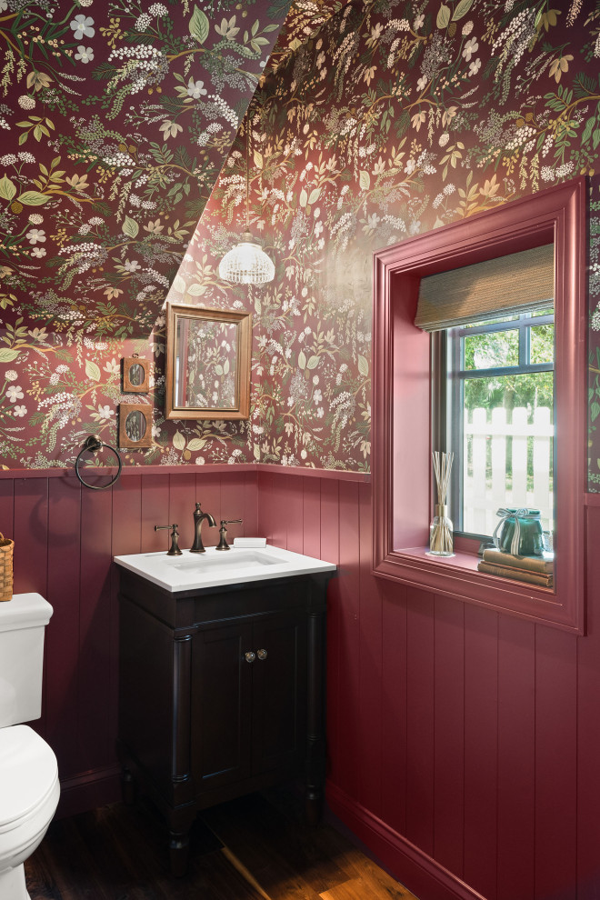 Inspiration for a timeless dark wood floor, brown floor, vaulted ceiling, wallpaper ceiling, wainscoting and wallpaper powder room remodel in Orlando with recessed-panel cabinets, black cabinets, a two-piece toilet, multicolored walls, an undermount sink, white countertops and a freestanding vanity
