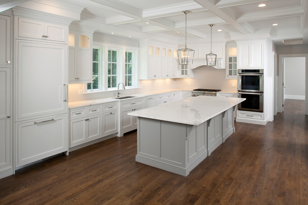 Large transitional l-shaped separate kitchen in Boston with an undermount sink, recessed-panel cabinets, white cabinets, marble benchtops, panelled appliances, dark hardwood floors, with island and brown floor.