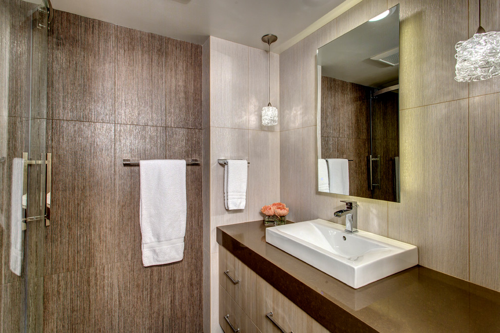 This is an example of a small contemporary 3/4 bathroom in Seattle with flat-panel cabinets, a corner shower, a one-piece toilet, brown tile, porcelain tile, brown walls, porcelain floors, a vessel sink, engineered quartz benchtops and beige cabinets.