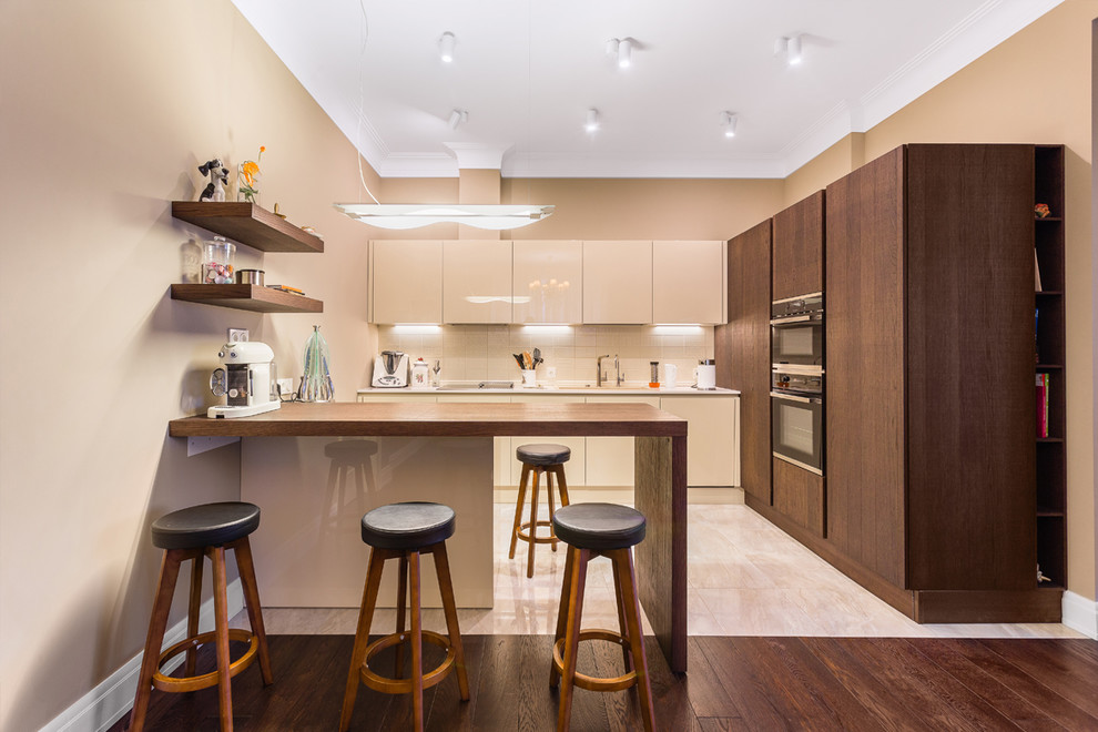 This is an example of a large contemporary l-shaped eat-in kitchen in Moscow with an undermount sink, flat-panel cabinets, beige cabinets, quartz benchtops, beige splashback, ceramic splashback, stainless steel appliances, porcelain floors, beige floor, beige benchtop and a peninsula.