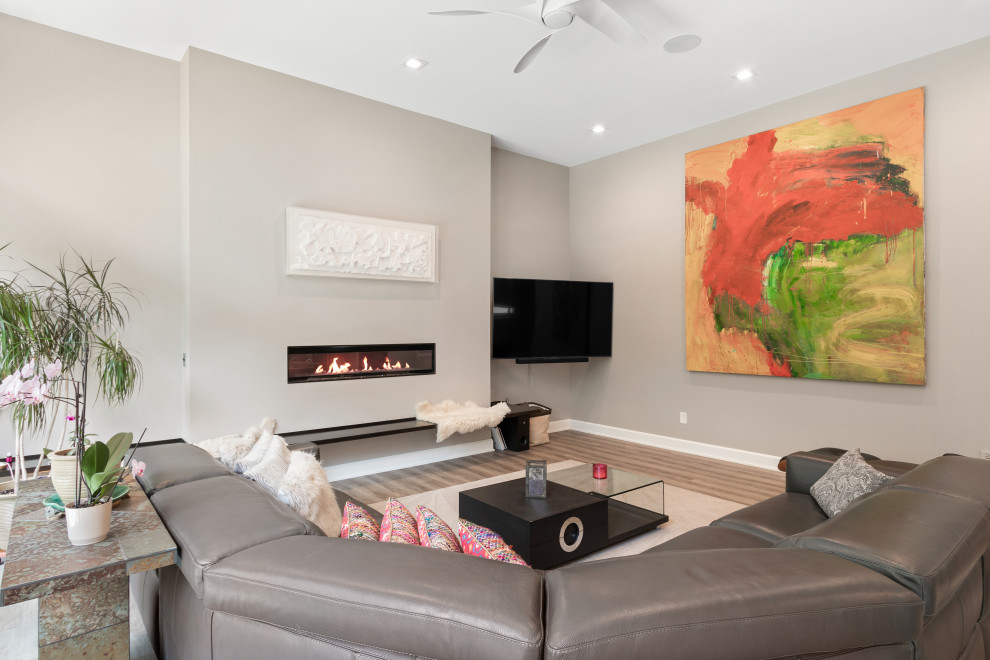 This is an example of a mid-sized contemporary formal open concept living room in Columbus with beige walls, medium hardwood floors, a ribbon fireplace, a wall-mounted tv and brown floor.