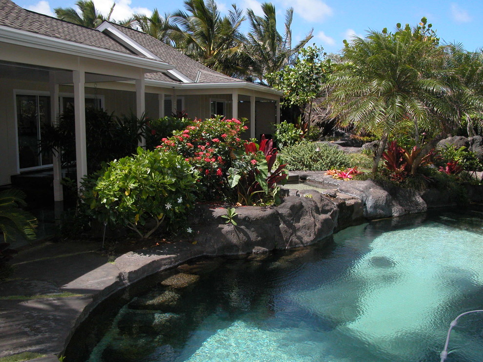 Photo of a mid-sized tropical courtyard kidney-shaped natural pool in Hawaii with a water feature and stamped concrete.