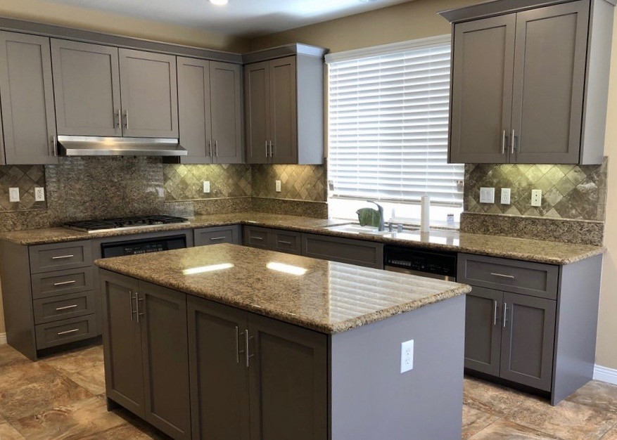 This is an example of a transitional u-shaped kitchen in Orange County with shaker cabinets, grey cabinets, granite benchtops, beige splashback, ceramic splashback, stainless steel appliances, ceramic floors, with island, beige floor and brown benchtop.