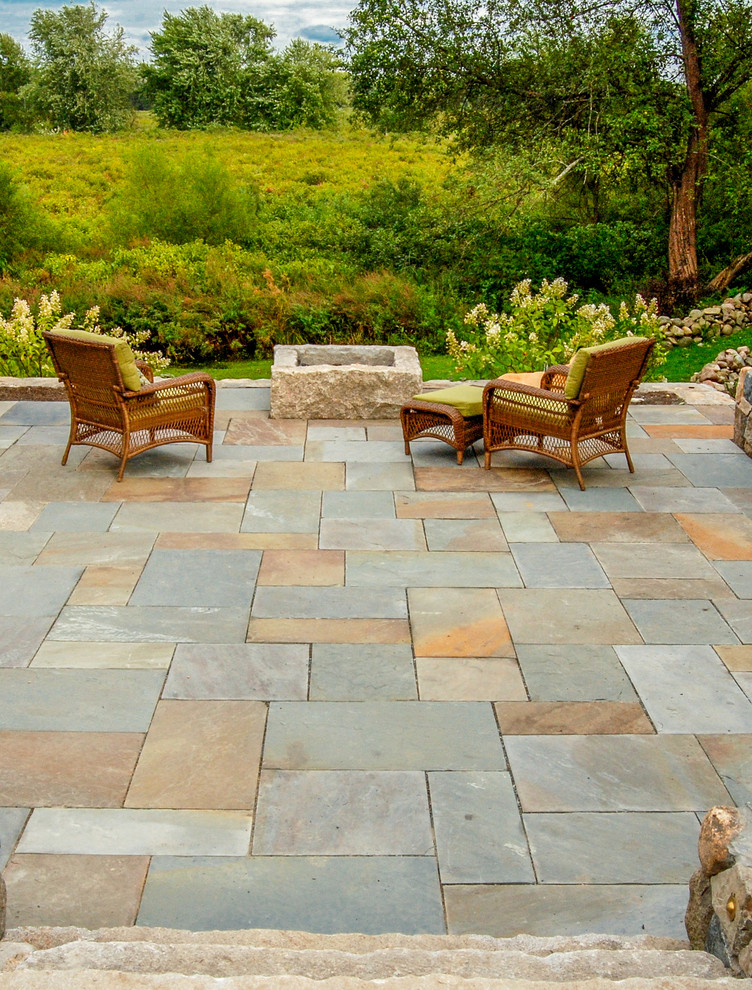 This is an example of a mid-sized country backyard patio in Boston with a fire feature and natural stone pavers.