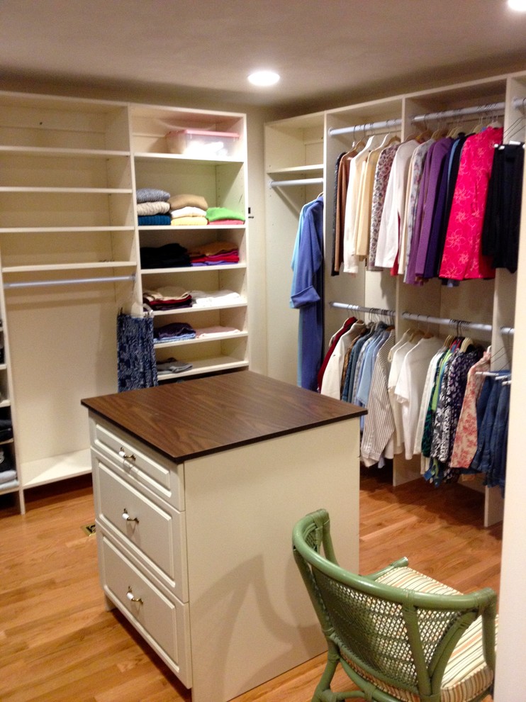 This is an example of a mid-sized traditional gender-neutral walk-in wardrobe in Boston with open cabinets, white cabinets and light hardwood floors.