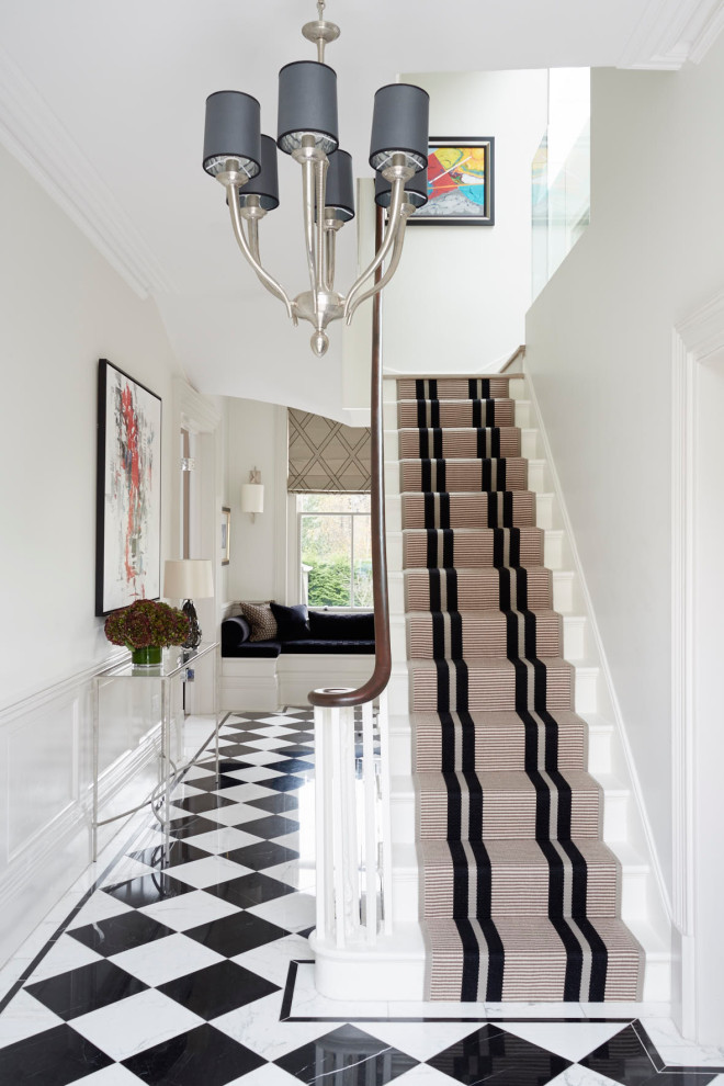 Large transitional entry hall in London with beige walls, marble floors, a single front door, a black front door and black floor.