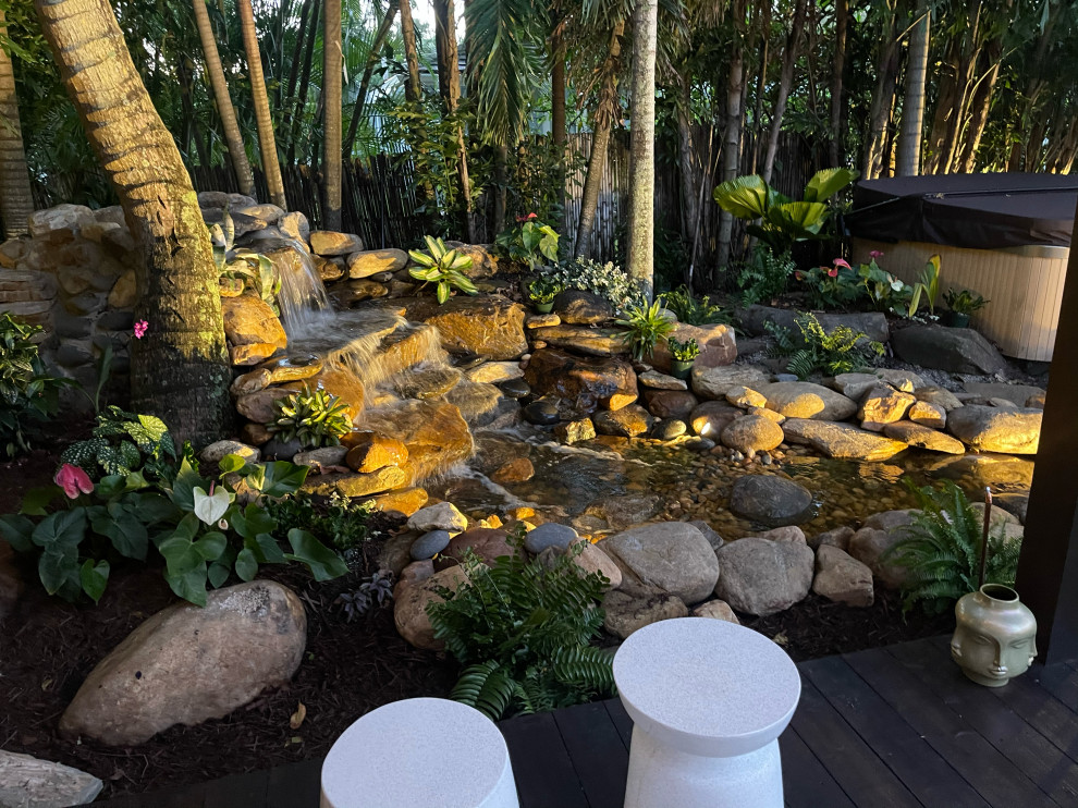 Cette photo montre un grand jardin arrière asiatique avec un bassin, des solutions pour vis-à-vis, pierres et graviers, un chemin, une cascade, une exposition partiellement ombragée et des pavés en pierre naturelle.