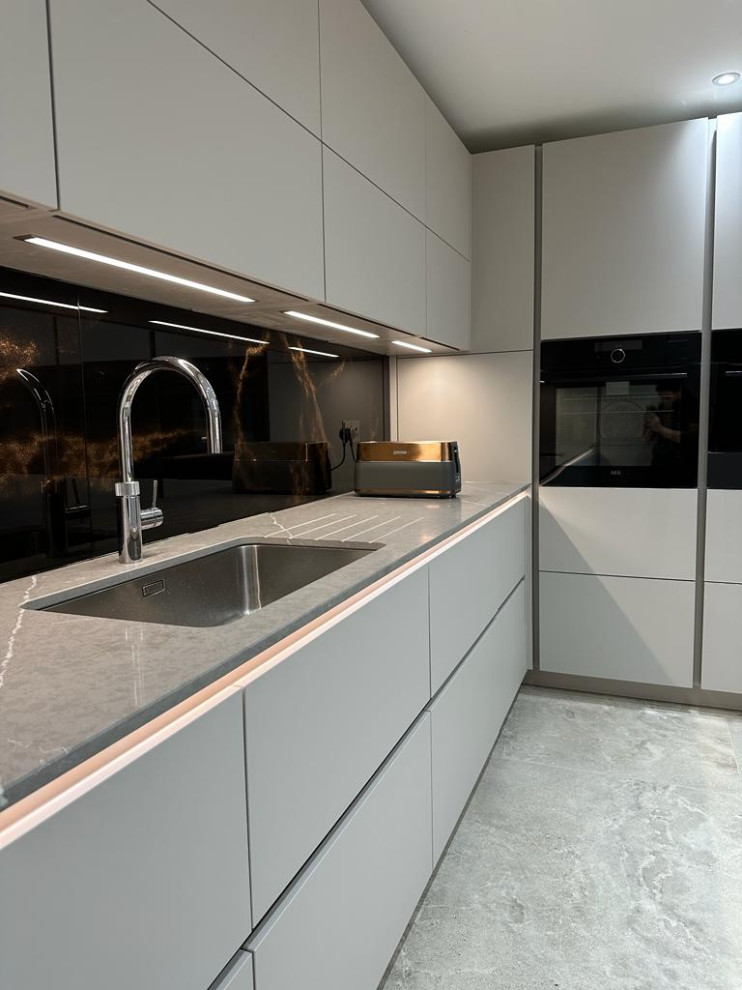 Einzeilige, Mittelgroße Moderne Küche mit integriertem Waschbecken, flächenbündigen Schrankfronten, grauen Schränken, Quarzit-Arbeitsplatte, Küchenrückwand in Braun, Glasrückwand, Kücheninsel und grauer Arbeitsplatte in Buckinghamshire