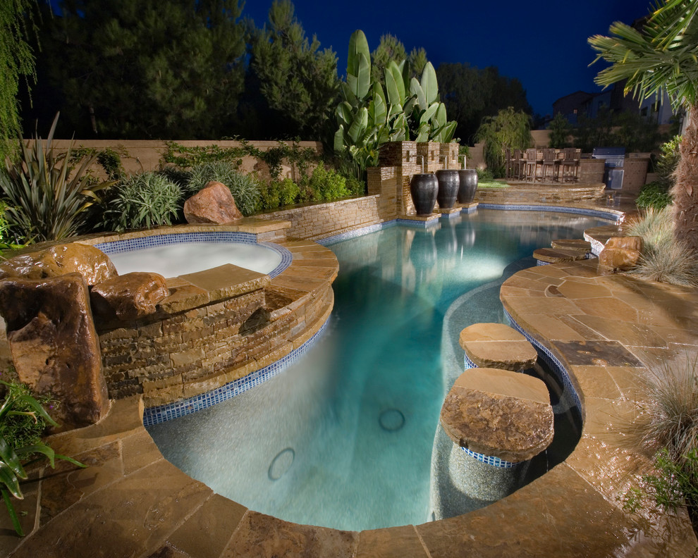 Inspiration for a mediterranean custom-shaped pool in Orange County with natural stone pavers and a hot tub.