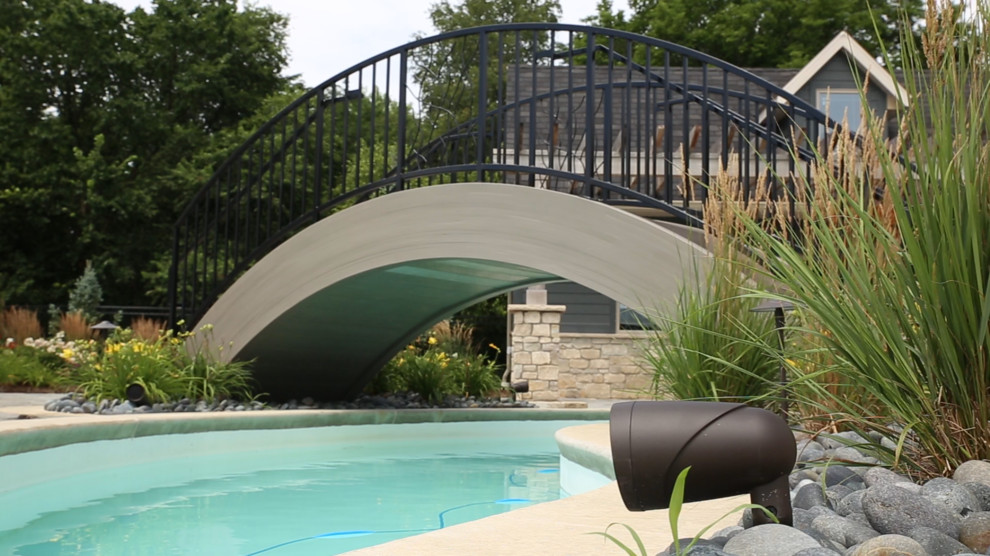 Mid-sized transitional backyard concrete and custom-shaped pool photo