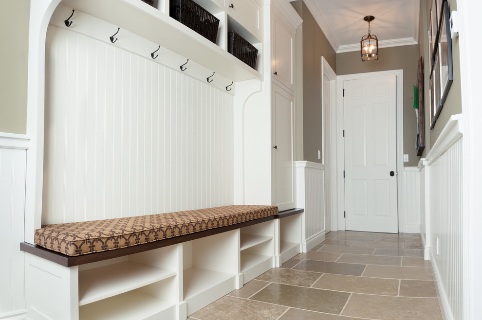 Design ideas for a transitional mudroom in New York with limestone floors, green walls and a white front door.