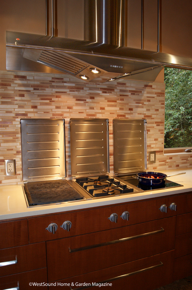 This is an example of a large contemporary u-shaped open plan kitchen in Seattle with an undermount sink, flat-panel cabinets, medium wood cabinets, quartz benchtops, multi-coloured splashback, matchstick tile splashback, stainless steel appliances, with island, cork floors, brown floor and beige benchtop.