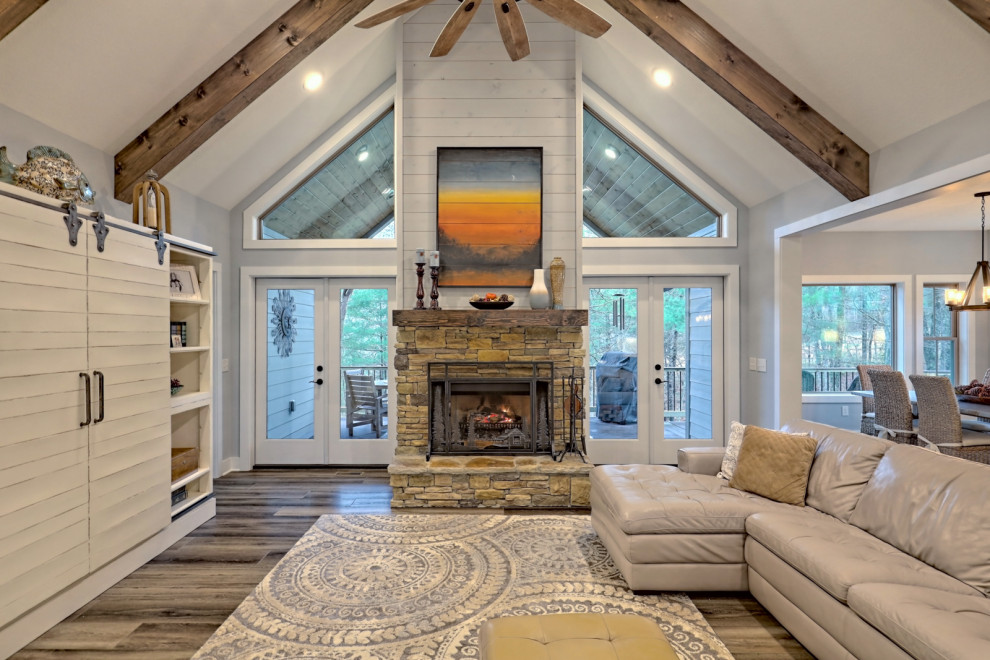 Design ideas for a mid-sized arts and crafts formal open concept living room in Atlanta with grey walls, vinyl floors, a standard fireplace, a stone fireplace surround, a built-in media wall, grey floor and exposed beam.
