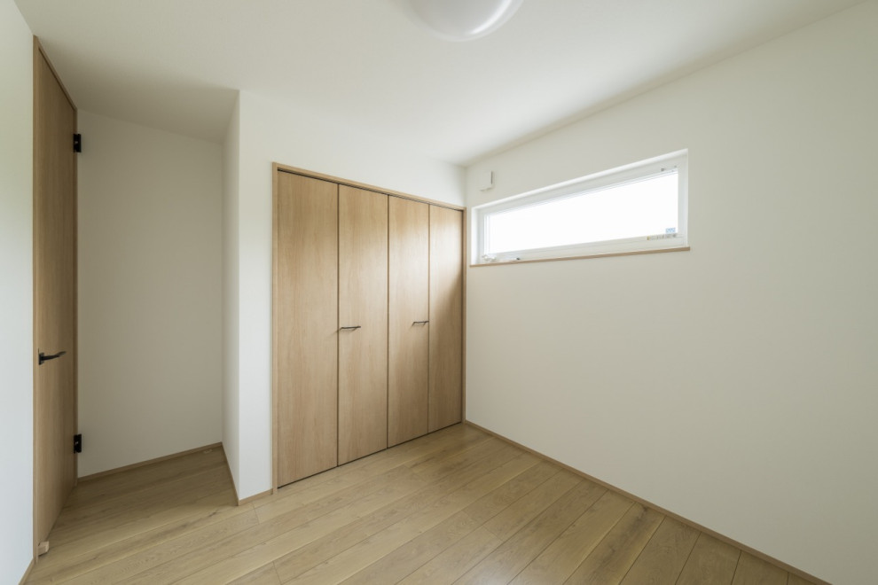 Modelo de dormitorio infantil blanco moderno de tamaño medio con paredes blancas, suelo de madera clara, suelo marrón, papel pintado y papel pintado