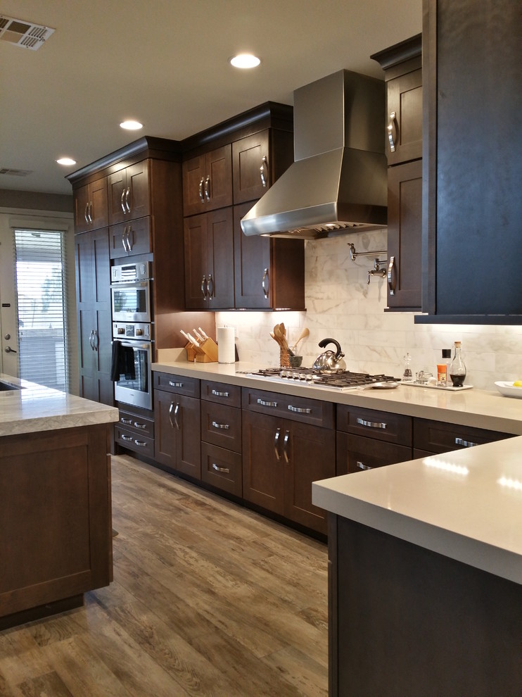 Inspiration for a large transitional l-shaped open plan kitchen in Las Vegas with an undermount sink, shaker cabinets, brown cabinets, quartzite benchtops, white splashback, marble splashback, stainless steel appliances, porcelain floors, with island, multi-coloured floor and grey benchtop.