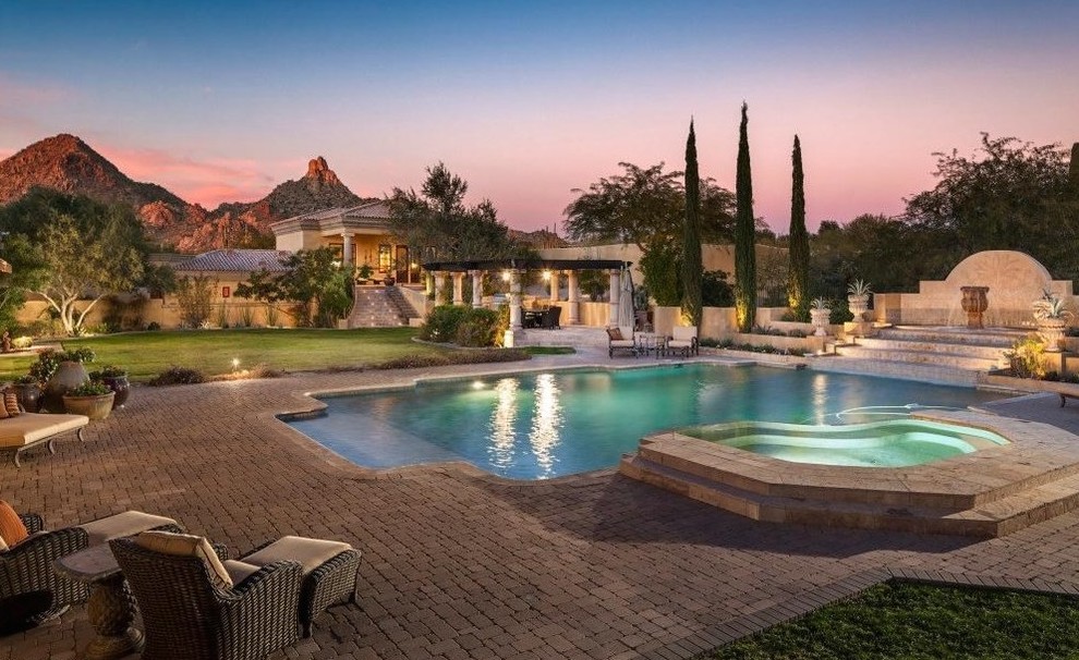 This is an example of an expansive traditional backyard full sun formal garden in Phoenix with a water feature and natural stone pavers.
