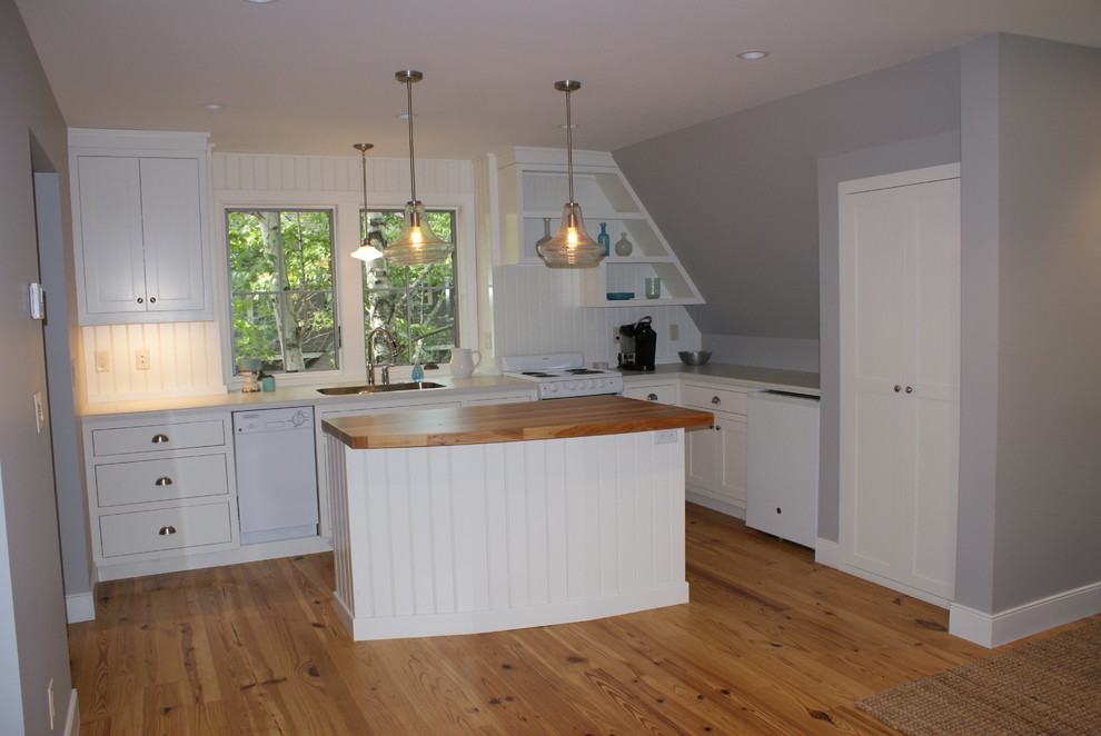 Small beach style l-shaped open plan kitchen in Minneapolis with an undermount sink, recessed-panel cabinets, white cabinets, laminate benchtops, white splashback, white appliances, light hardwood floors and with island.