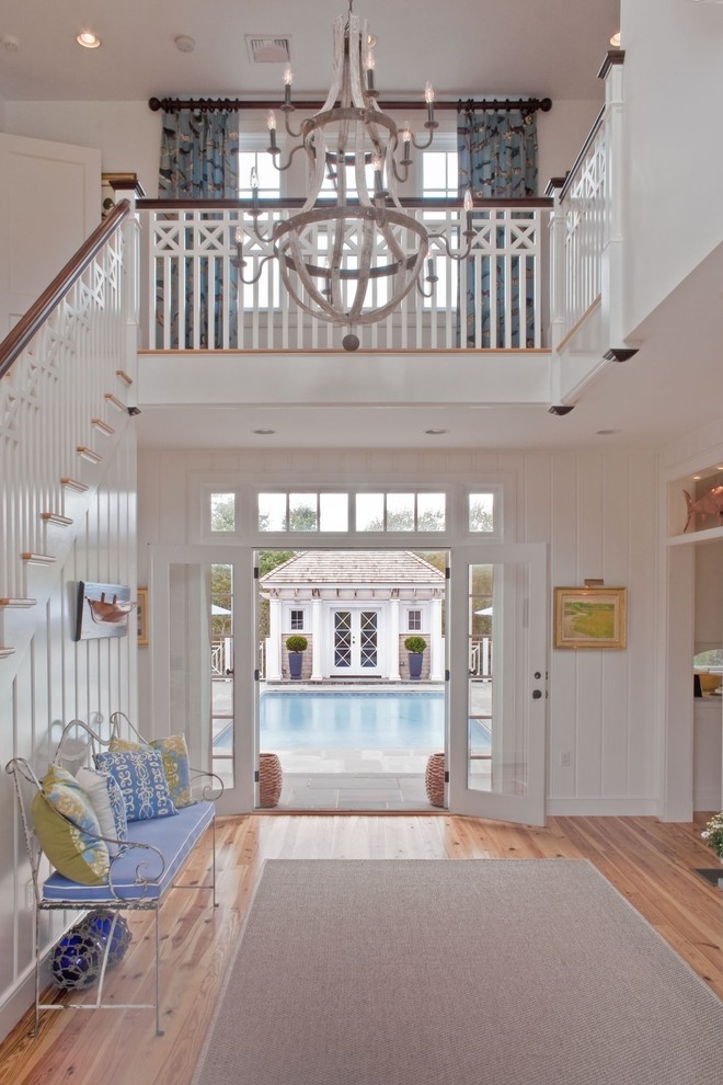 This is an example of a beach style foyer in Providence with white walls, light hardwood floors, a double front door and a glass front door.
