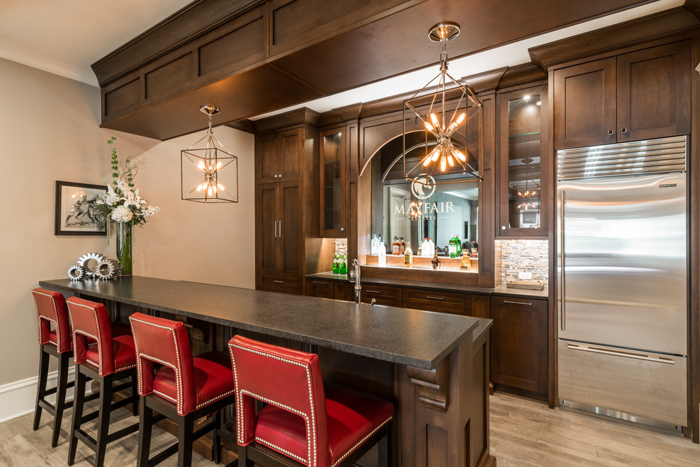 This is an example of a mid-sized transitional galley seated home bar in Atlanta with a drop-in sink, shaker cabinets, dark wood cabinets, granite benchtops, grey splashback, ceramic floors and grey floor.