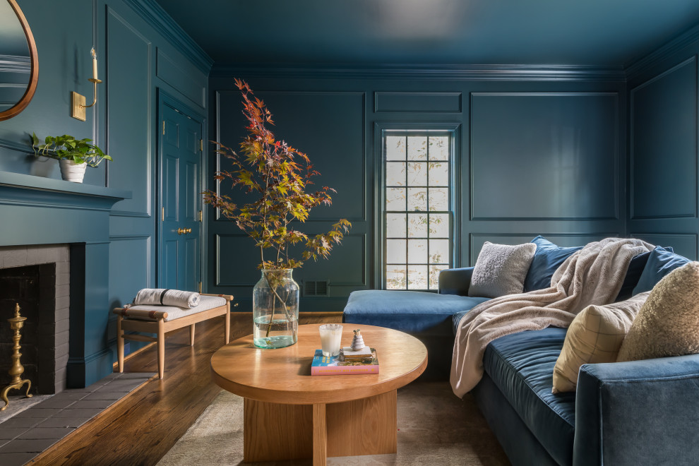 Idee per un soggiorno chic di medie dimensioni con libreria, pareti blu, parquet scuro, camino classico, cornice del camino in mattoni, pavimento marrone e pannellatura