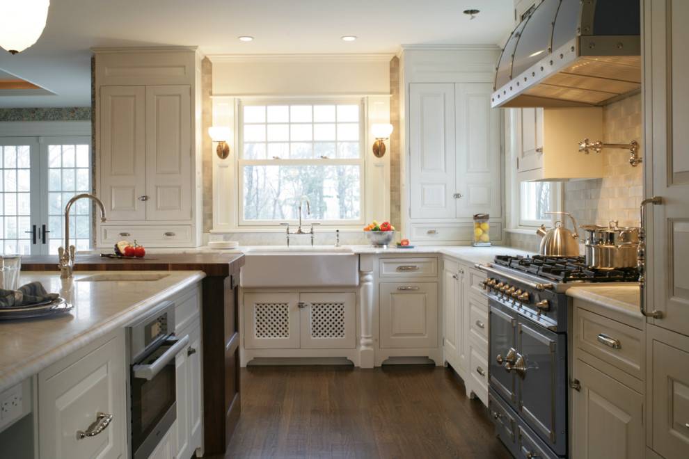 This is an example of a traditional l-shaped eat-in kitchen in New York with a farmhouse sink, raised-panel cabinets, white cabinets, marble benchtops, grey splashback, ceramic splashback and coloured appliances.