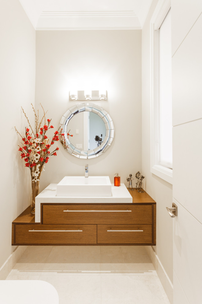 На фото: туалет в современном стиле с фасадами цвета дерева среднего тона, белой плиткой, белыми стенами, белой столешницей, подвесной тумбой и белым полом
