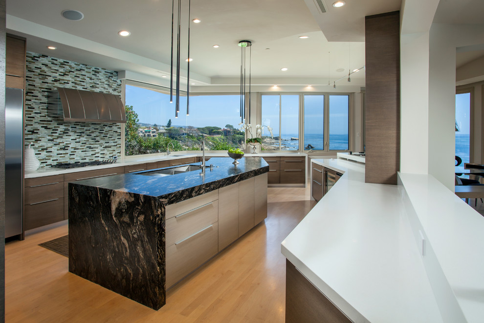 Large contemporary eat-in kitchen in Orange County with a triple-bowl sink, flat-panel cabinets, light wood cabinets, green splashback, mosaic tile splashback, stainless steel appliances, light hardwood floors and with island.