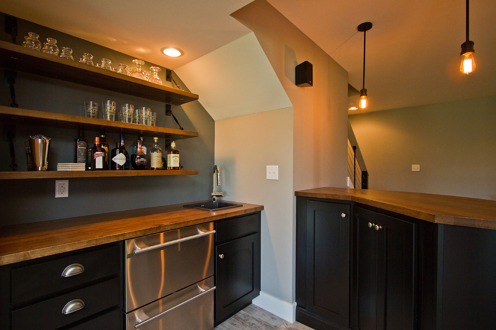 Large arts and crafts single-wall wet bar in Other with carpet, a drop-in sink, recessed-panel cabinets, black cabinets, wood benchtops, grey splashback and brown benchtop.