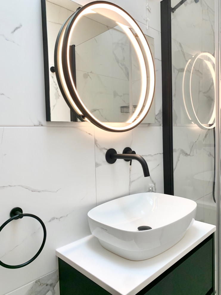 Modern inredning av ett litet vit vitt en-suite badrum, med släta luckor, svarta skåp, en öppen dusch, en toalettstol med hel cisternkåpa, svart och vit kakel, porslinskakel, klinkergolv i porslin, marmorbänkskiva och dusch med gångjärnsdörr
